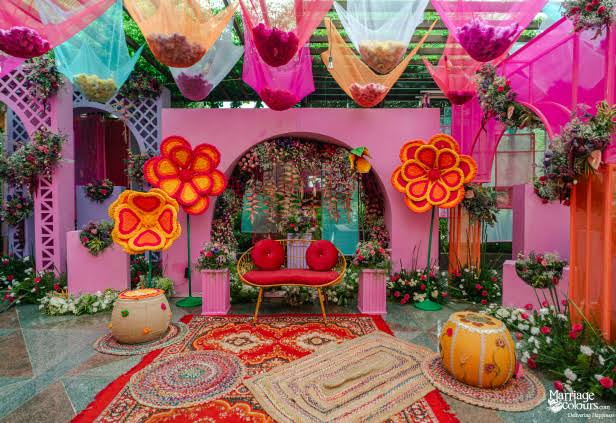 Colourful mehndi event decoration with vibrant fabrics and florals